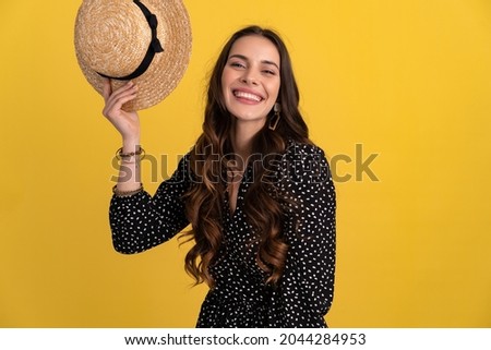 portrait of pretty attractive woman posing isolated on yellow background wearing black dotted dress and straw hat stylish boho trend, spring summer fashion style accessories, smiling happy mood