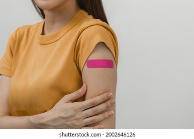 Portrait Of Pretty, Beautiful Asian Young, Teenage Attractive After Getting, Receive Anti Virus Vaccine Covid-19. Showing Arm On Pink Bandage In Yellow T-shirt Isolated On White Background, Copy Space
