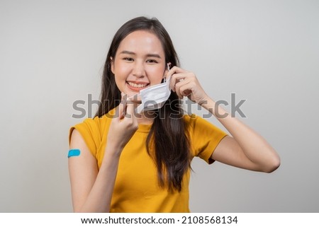Portrait of pretty, beautiful asian young, teenage take of the mask after getting, receive anti virus vaccine covid-19. Showing arm on white bandage isolated on white background,copy space.Health care