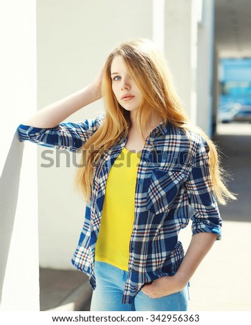 Portrait pretty blonde young girl wearing a checkered shirt in city