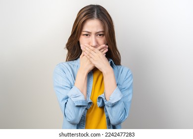 Portrait of pretty brunette hair, disgust smell bad breath strong asian young woman, girl covering, close her mouth with hand, expression face disgusting, dislike odor. Isolated on white background. - Shutterstock ID 2242477283