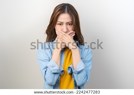 Portrait of pretty brunette hair, disgust smell bad breath strong asian young woman, girl covering, close her mouth with hand, expression face disgusting, dislike odor. Isolated on white background.
