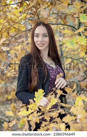 Portrait of a pretty brunette posing among autumn tree branches