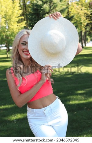 Portrait of pretty caucasian woman with hat standing in the park. Attractive beautiful girl.