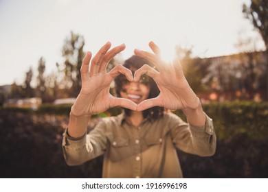 Portrait of pretty cheerful curly hairstyle dark skin lady fingers show heart shape sunny weekend day outdoors