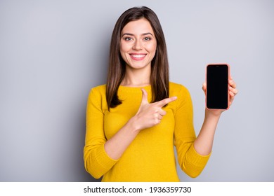 Portrait of pretty content cheerful girl holding in hand demonstrating gadget advert isolated over grey color background - Powered by Shutterstock