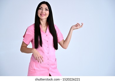 Portrait of a pretty cosmetologist doctor brunette girl with good makeup with long hair on a white background in a medical pink coat. Stands in different poses with emotions. - Shutterstock ID 1520226221
