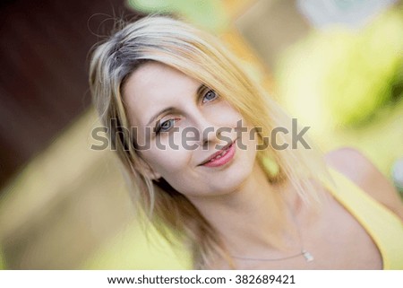 Similar – Young blonde woman portrait laughing outdoors sitting in a garden, and looking at camera.