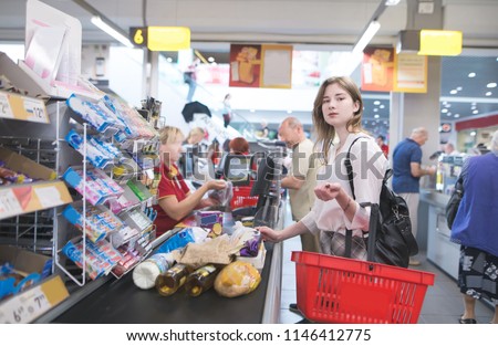 Portrait of a pretty girl buying products at the checkout in the supermarket and looking at the camera. Payment for purchases at the checkout in the store