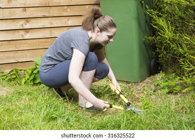 Portrait Of Pretty Girl Cutting Grass With Horticultural Sundry Outdoors