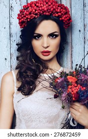 portrait of pretty girl with wreath of red berries and pigtail . Fashionable image , model with braid and red lips