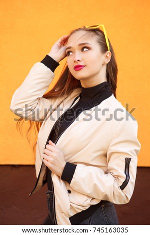Portrait of pretty hipster girl in sunglasses on orange background. Perfect summer make-up and style