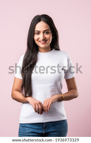 Portrait of Pretty Indian modern girl or young woman standing against pink background. Studio shot