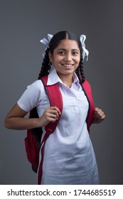 Portrait Of Pretty Indian School Girl Against Grey Background