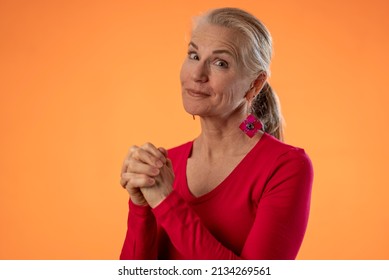 Portrait Of Pretty Mature Woman Hoping And Praying For Good Outcome Isolated On Solid Orange Background With Copy Space.