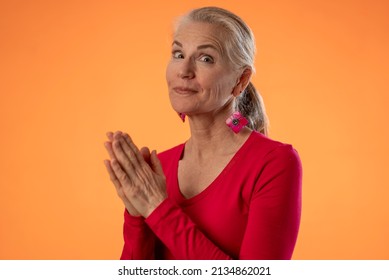 Portrait Of Pretty Mature Woman Hoping And Praying For Good Outcome Isolated On Solid Orange Background With Copy Space.