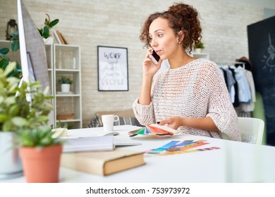 Portrait of pretty mixed race woman speaking by phone discussing color palette for interior design, holding color swatches - Shutterstock ID 753973972