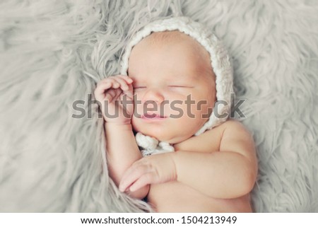 Newborn baby girl sleeping lying on bed next to mother’s hand