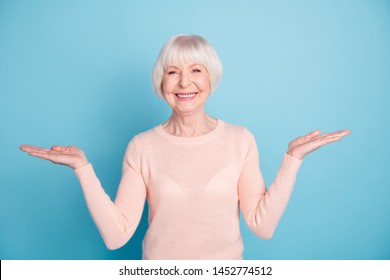 Portrait Of Pretty Old Woman Holding Hands With Toothy Smile Wearing Pastel Jumper Isolated Over Blue Background