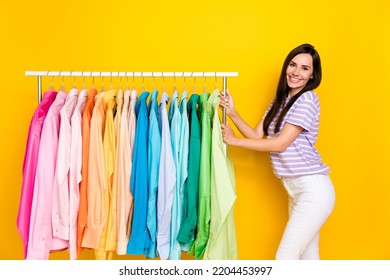 Portrait Of Pretty Positive Good Looking Lady Hand Arm Touch Rack Trendy Colorful Shirts Isolated On Yellow Color Background