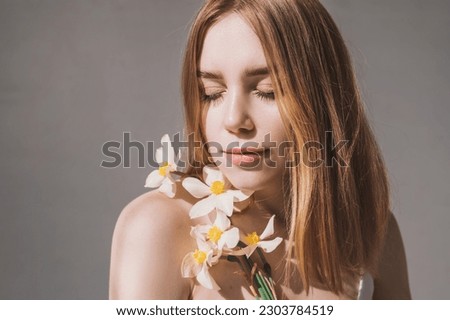 Portrait of a pretty red-haired girl with freckles in flowers with hard shadows and bright sunbeams. Natural beauty without retouching. Self acceptance and caring for your body