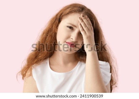 Portrait of pretty redhead woman suffering from headache on pink background