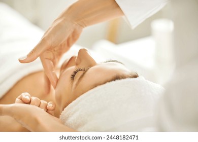 Portrait of pretty relaxed young woman lying with closed eyes having facial massage in spa salon. Female client enjoy receiving skin care procedure treatment. Wellness and beauty day concept. - Powered by Shutterstock