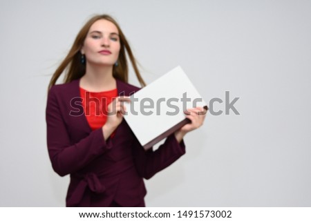 Portrait of a pretty secretary manager brunette girl with long flying hair in a burgundy business suit with a folder on a white background. Smiling, showing emotions.