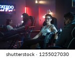 Portrait of a pretty short hair teen girl getting a tattoo in arm at beauty parlour. Young millennial gay woman gets body art at night at tattoo studio. Portrait of woman looking at camera