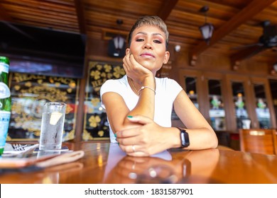 Porträt einer ziemlich lächelnden malaysischen Frau, sitzend an einem Tisch in einem Café in Kuala Lumpur, Malaysia. Ein junges charmantes asiatisches Mädchen, das allein an einem Holztisch in einem Restaurant sitzt.  