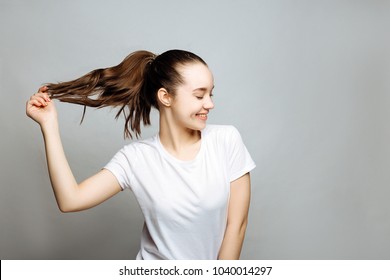Portrait of a pretty smiling woman brunette in a white t-shirt posing isolated on a white background. the girl looks to the right and shows the hair.