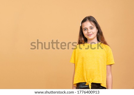 Portrait of pretty teenage girl in yellow t-shirt isolated on orange background with copyspace