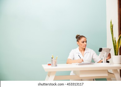 Portrait Of A Pretty Therapist Working At A Health And Beauty Clinic And Spa Taking Notes In A Front Desk