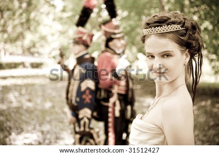 Portrait of pretty woman dressed in vintage dress and accessories. Dueling hussars on the background.