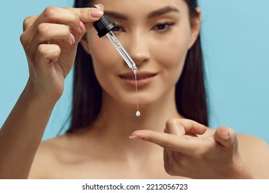 Portrait of pretty woman dripping serum on her finger. - Powered by Shutterstock