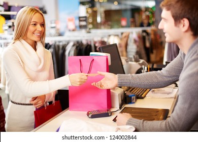 Portrait Of Pretty Woman Giving Credit Card To Shop Assistant While Paying For Her Purchase