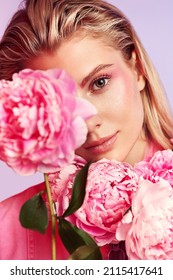Portrait of pretty woman with pink peony. Healthy skin and pink make up. Pink and purple background. Studio photoshoot.                                         