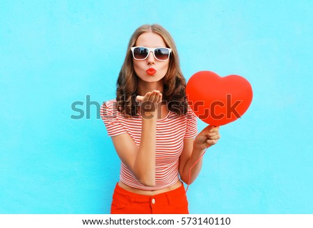 Portrait pretty woman sends air kiss with red balloon heart shape over blue background Сток-фото © 