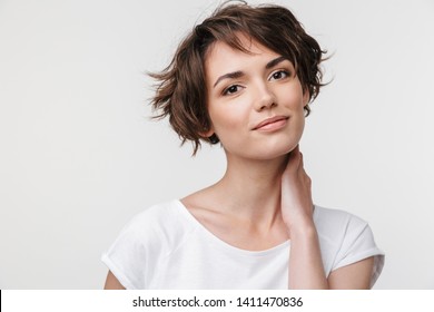 Portrait of pretty woman with short brown hair in basic t-shirt looking at camera while standing isolated over white background - Shutterstock ID 1411470836