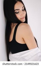 Portrait Of Pretty Woman In Studio. Beautiful Brunette Girl In Black Topic. White Background Of Cyclorama