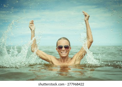 A portrait of a pretty woman swimming in the sea with sunglasses on her face