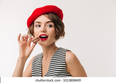 Portrait of a pretty woman wearing red beret eating cookies isolated over white background - Powered by Shutterstock