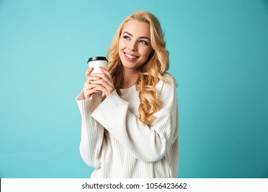 Portrait Of A Pretty Young Blonde Woman In Sweater Holding Takeaway Coffee Cup Isolated Over Blue Background