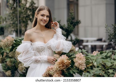 Portrait of pretty young bride in hydrangea blossom. Wedding dress with neckline. wedding dress with neckline decorated with lace
