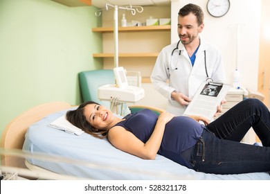 Portrait of a pretty young Hispanic pregnant woman lying on a bed next to her obgyn in a hospital