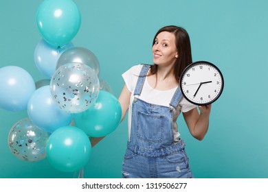 Portrait Of Pretty Young Woman In Denim Clothes Holding Round Clock And Celebrating With Colorful Air Balloons Isolated On Blue Turquoise Background. Birthday Holiday Party, People Emotions Concept