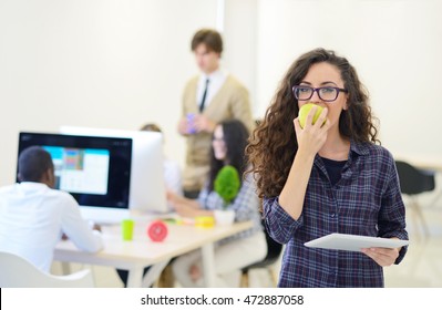 Portrait Of Pretty Young Woman Eating An Apple In Her Office.