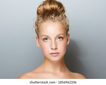 Portrait Of Pretty Young Woman With High Bun Hairstyle Over Gray Background