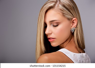 Portrait of a pretty young woman with long blond hair and closed eyes on gray background