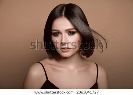 Portrait of pretty young woman with short hair on pastel brown background